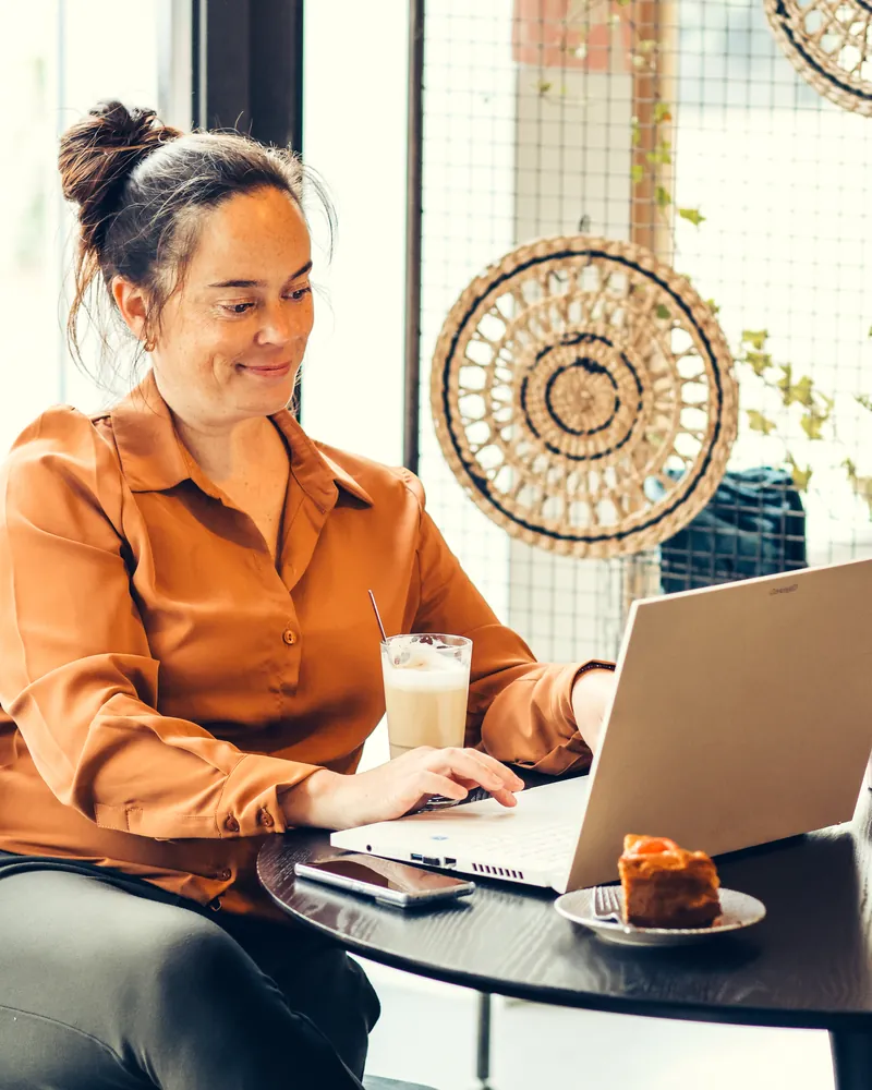 Website laten maken bij SjopSjop Webdesigner Molina van SjopSjop werkt lachend op haar laptop aan een nieuwe website voor een ondernemer