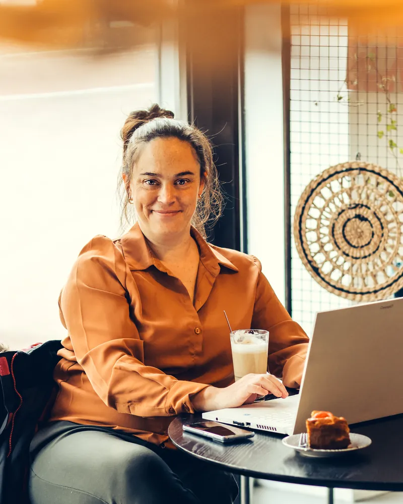 WooCommerce webshop laten maken bij SjopSjop Molina van SjopSjop werkt in een lunchroom op haar laptop aan een WooCommerce webshop